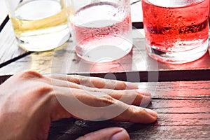 Many glasses of cocktails with hand on tray on table