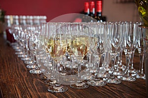 Many glasses with white wine on buffet table. Soft focus, selective focus