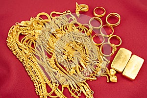 Many gold necklaces and gold bars on red velvet cloth