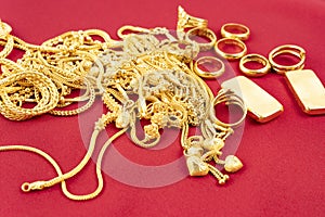 Many gold necklaces and gold bars on red velvet cloth