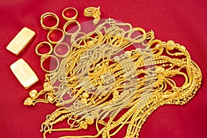 The many gold necklaces and gold bars on red velvet fabric background