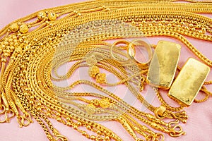 The Many gold necklaces and gold bars on red velvet fabric background