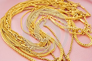 The Many gold necklaces on pink color cloth background