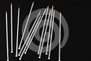 Many gray pencils close-up against a black background, top view