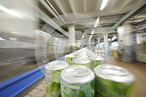 Many green cans with drinks go on conveyor