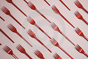 Many green plasic forks  on pink background, top view.  toned in red