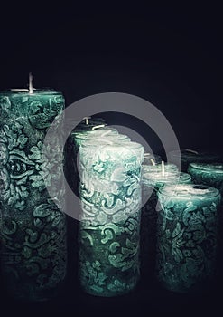 Many green wax candles with a pattern on a black background