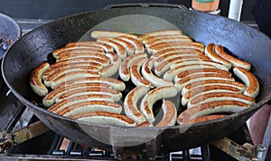 Many grilled sausages, austrian bratwursts , in a large black pan in a street food shop