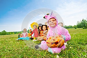 Many Halloween kids wear costumes sit in long row