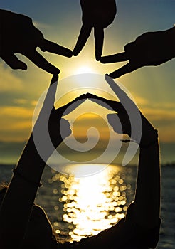 Many hands connecting to star shape at sunset, Teamwork Concept