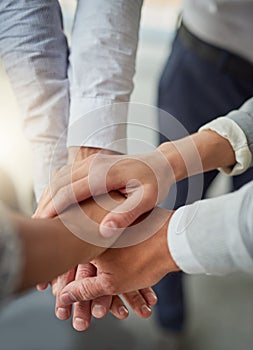 Many hands make success happen. a group of colleagues joining hands in solidarity in a modern office.