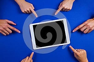 Many hands pointing to white tablet computer with blank screen on blue background