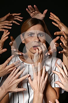 Many hands stretched to woman on dark background. Panic attack