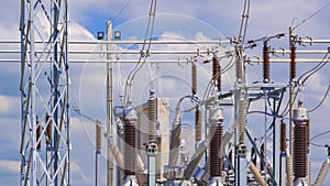 Many high voltage electrical component and insulators with electric pylon in power substation against cloudy sky background