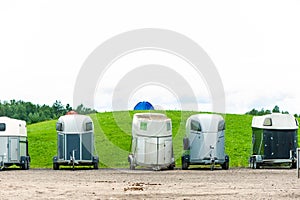 Many horse trailers in the green park outdoors.