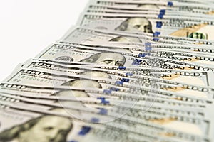 Many hundred dollar banknotes spread on white surface