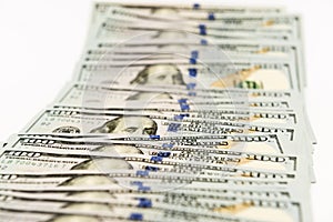 Many hundred dollar banknotes spread on white surface