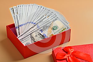 Many hundred dollar bills in a gift box