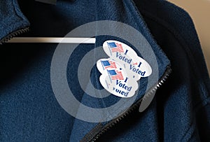 Many I Voted stickers on blue jacket hung on hanger