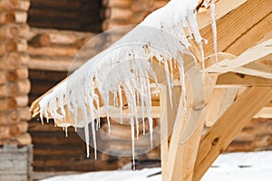 Many icicles melt on the wooden roof with water drops. Spring is comming.