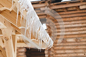 Many icicles melt on the wooden roof with water drops. Spring is comming.