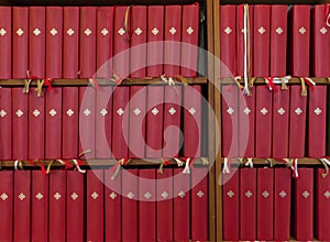 Many identical red books with bookmarks on the shelf