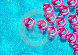 Many inflatable flamingo doughnut buoys in a pool