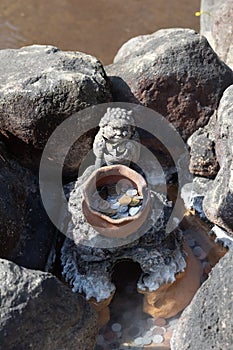 Many Japanese coins in pond with clay jar and statue