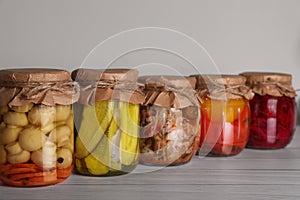 Many jars with preserved vegetables on white wooden table