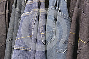 Many jeans hanging on arack. Row of pants denim jeans hanging in closet, concept of buy , sell , shopping and jeans