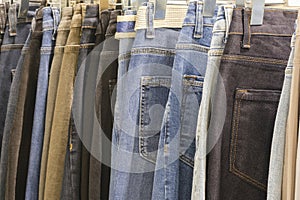 Many jeans hanging on arack. Row of pants denim jeans hanging in closet, concept of buy , sell , shopping and jeans fashion