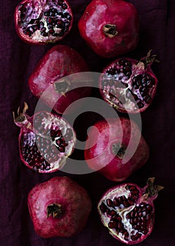 Many juicy red pomegranates lie on cherry natural cloth