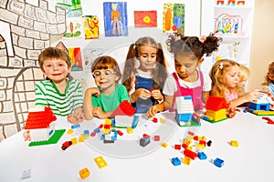 Many kids play with plastic blocks in classroom