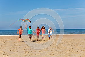 Many kids run on the beach with color kite