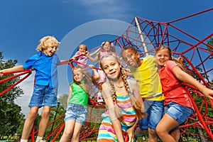 Many kids stand on red ropes together in park