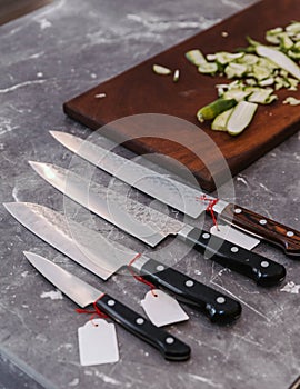 Many kinds of super sharp Japanese kitchen knives with ultra thin slice zucchini on wooden chopping board
