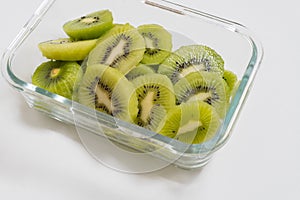 Many kiwi slices are placed in a glass crisper. Kiwifruit slices without peel