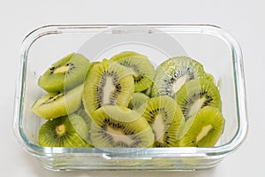 Many kiwi slices are placed in a glass crisper. Kiwifruit slices without peel