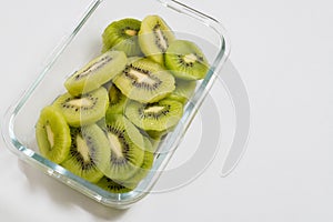 Many kiwi slices are placed in a glass crisper. Kiwifruit slices without peel