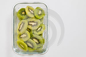 Many kiwi slices are placed in a glass crisper. Kiwifruit slices without peel