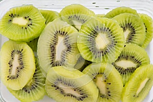 Many kiwi slices are placed in a glass crisper. Kiwifruit slices without peel