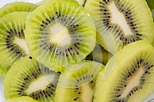 Many kiwi slices are placed in a glass crisper. Kiwifruit slices without peel