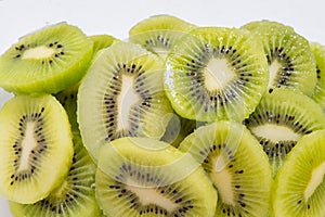 Many kiwi slices are placed in a glass crisper. Kiwifruit slices without peel