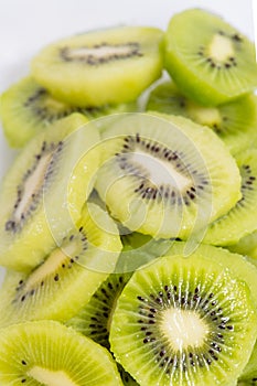 Many kiwi slices are placed in a glass crisper. Kiwifruit slices without peel