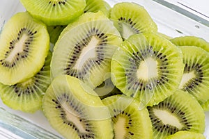 Many kiwi slices are placed in a glass crisper. Kiwifruit slices without peel