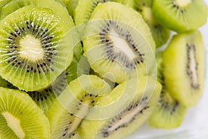 Many kiwi slices are placed in a glass crisper. Kiwifruit slices without peel