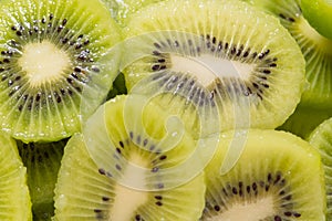 Many kiwi slices are placed in a glass crisper. Kiwifruit slices without peel