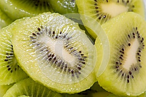 Many kiwi slices are placed in a glass crisper. Kiwifruit slices without peel