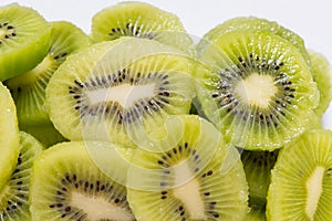 Many kiwi slices are placed in a glass crisper. Kiwifruit slices without peel