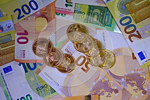 Many Krugerrand and Dollar gold coins are lying on various spread out Euro banknotes